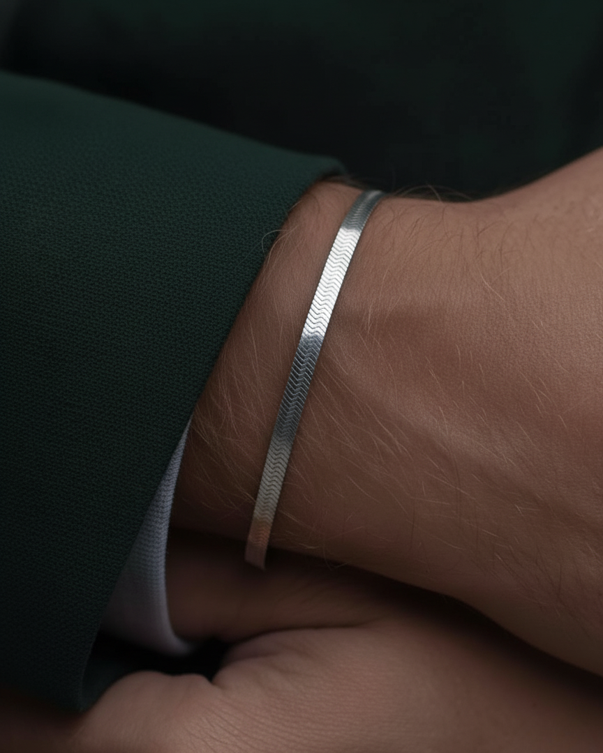 Close-up of a hand wearing a silver bracelet on a dark background